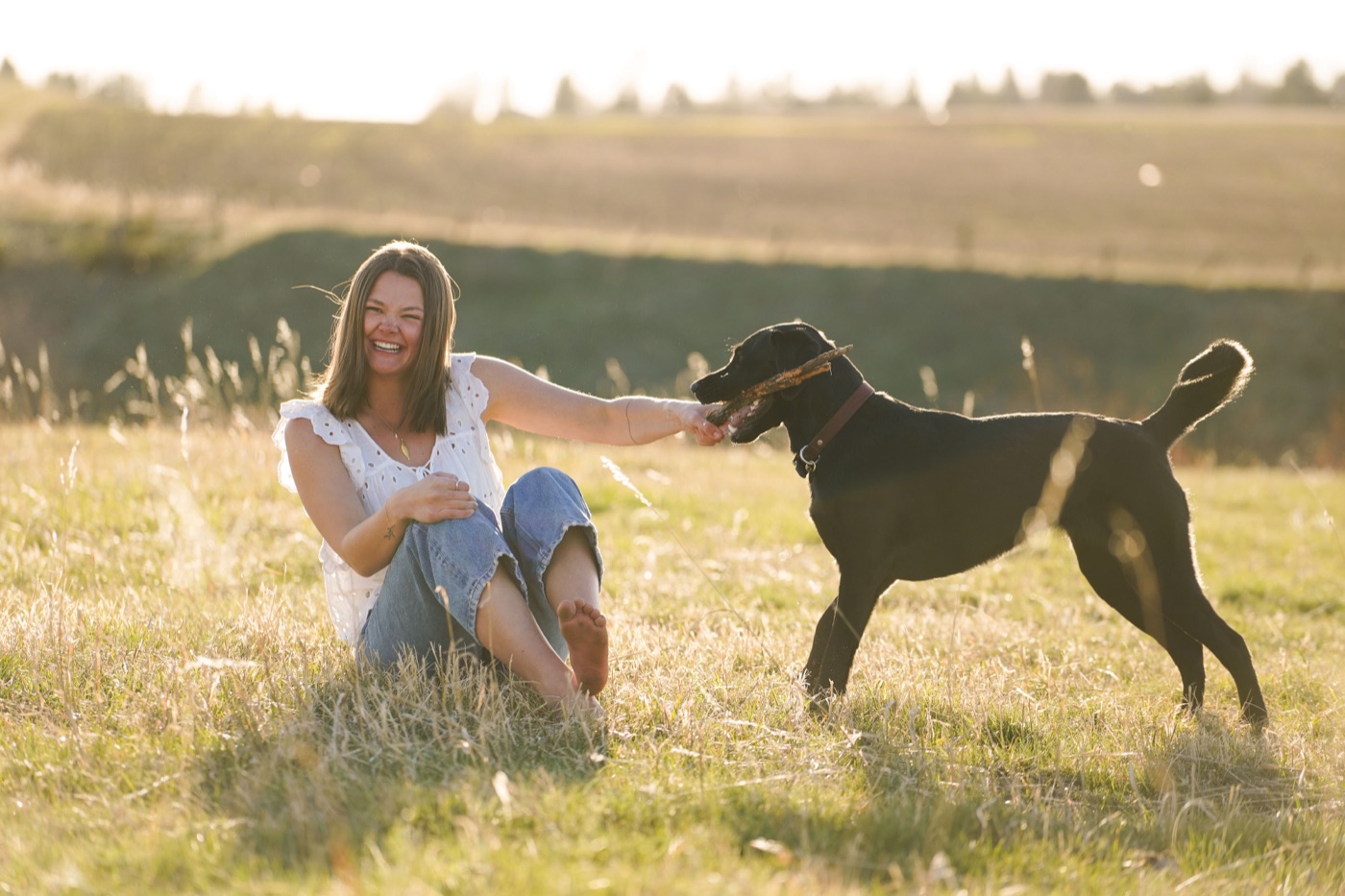 Audrey Warren, founder of Après Sparkles, laughing in a golden Montana field with her dog