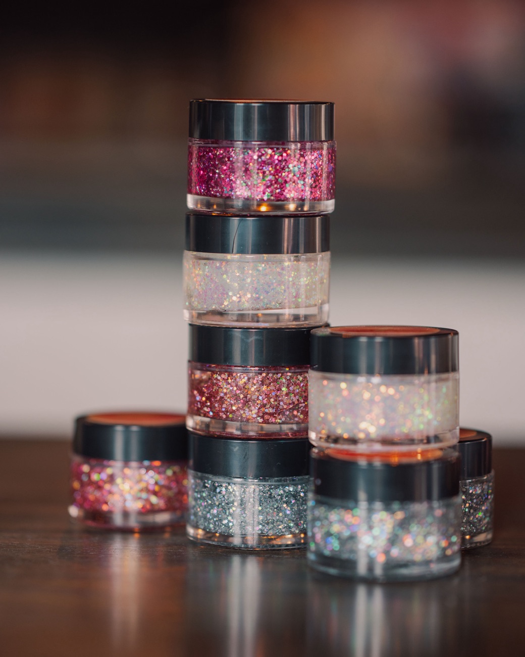 A stack of Après Sparkles glitter jars in pink, iridescent, rose, silver and gold