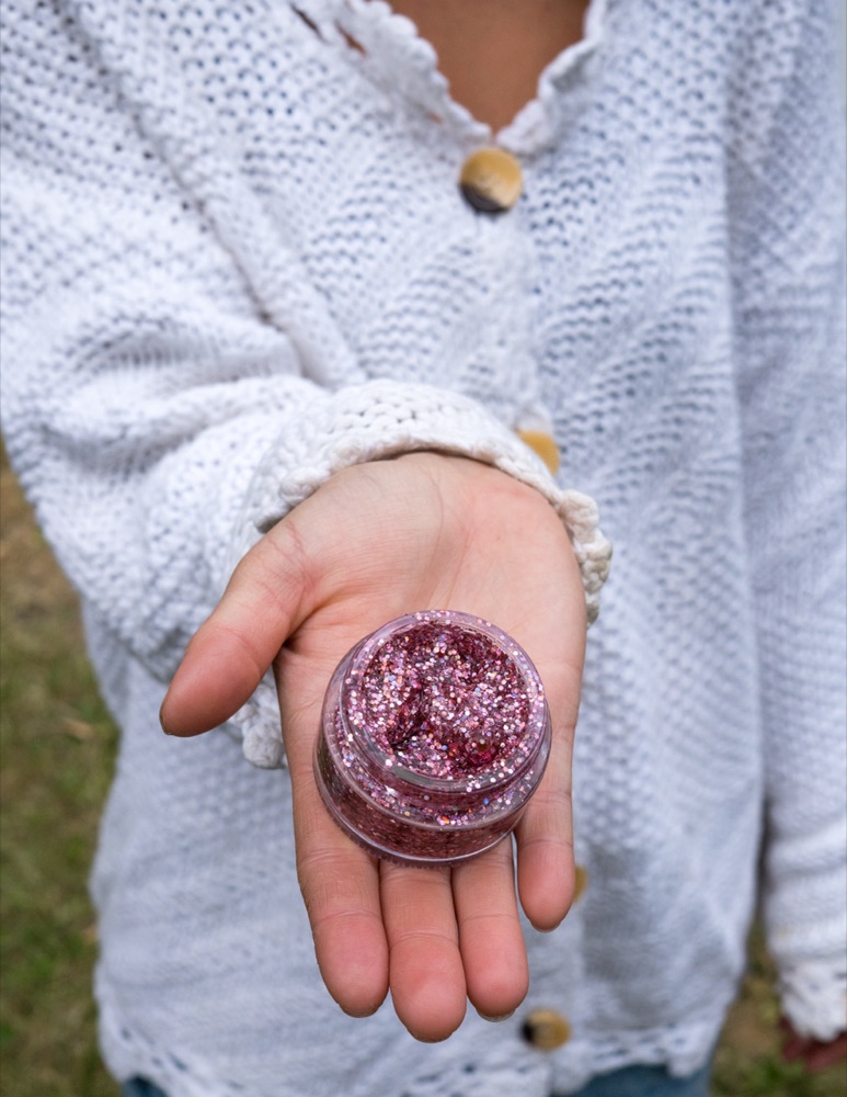 Alpen Glow — a jar of rose biodegradable face & body glitter held in hand