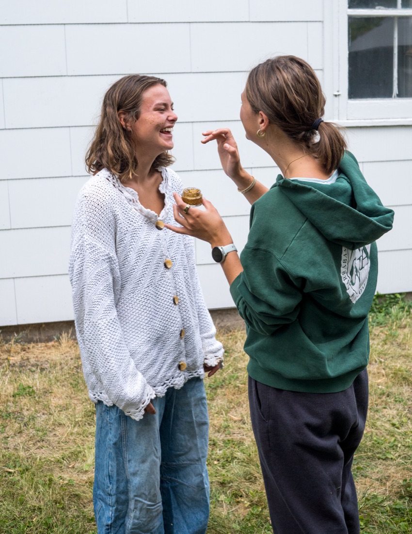 Two friends laughing while applying Après Sparkles glitter outdoors